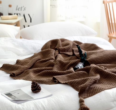 Strikket pledd med dusker i sofaen